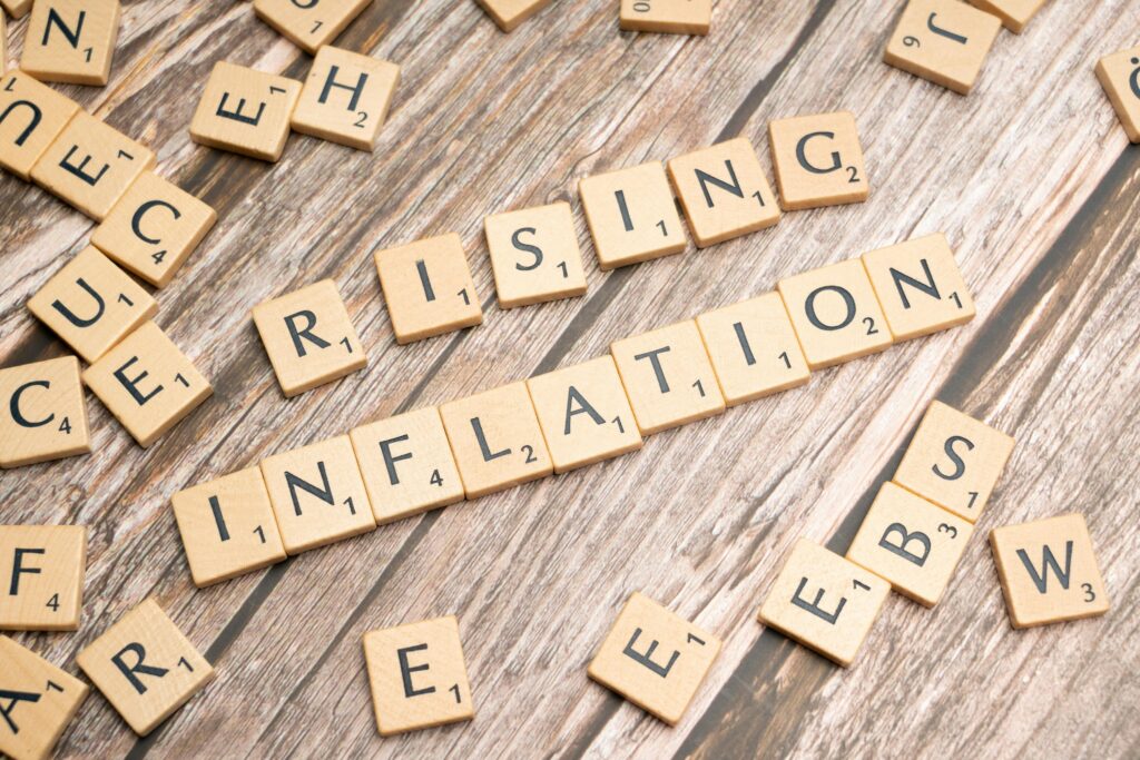 Wooden letter tiles spell 'rising inflation' symbolizing economic concerns.